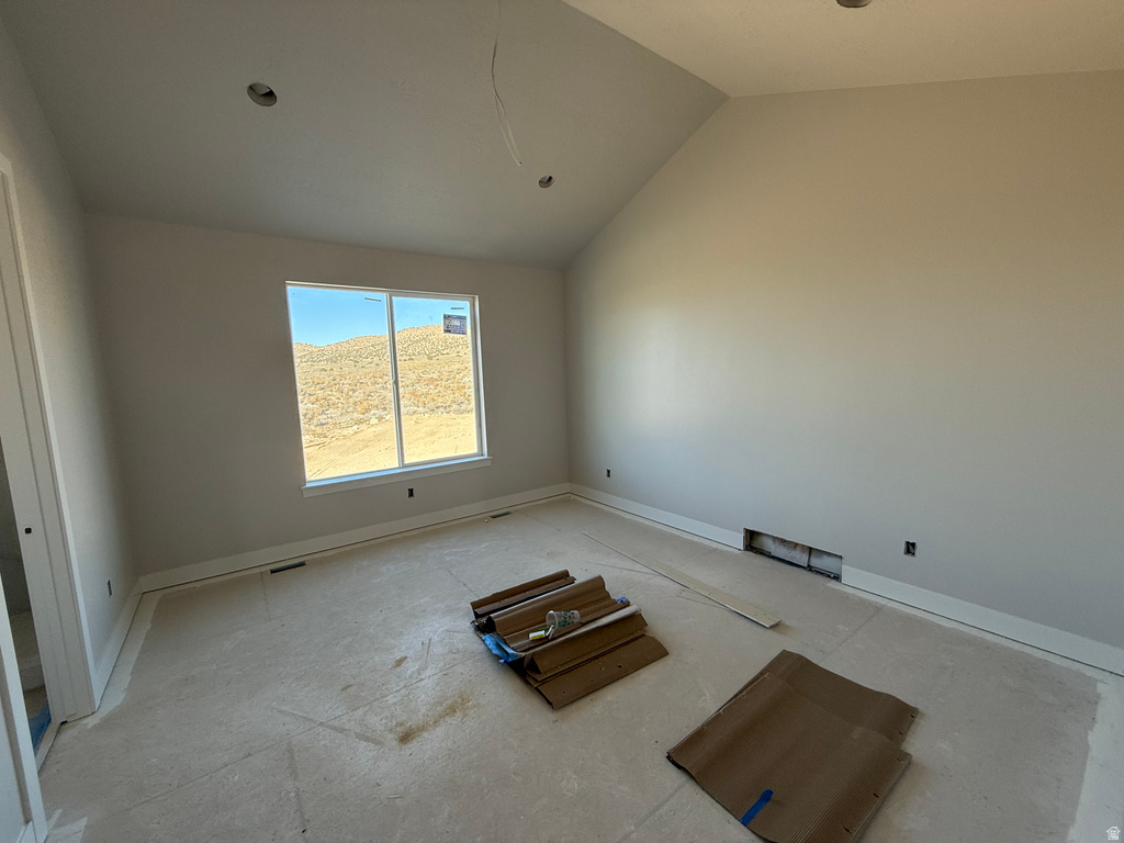Unfurnished room with vaulted ceiling and baseboards
