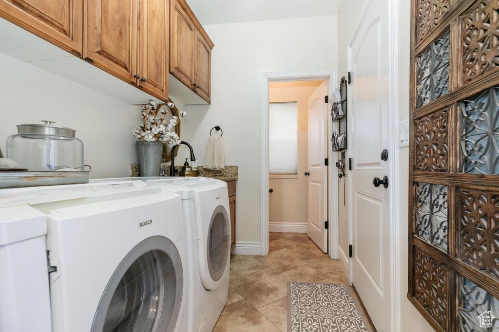 Laundry room featuring separate washer and dryer, cabinet space, and light tile patterned flooring
