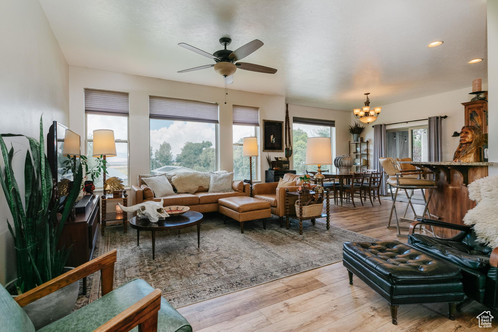 Living area with light wood-style floors, a ceiling fan, recessed lighting, and a chandelier