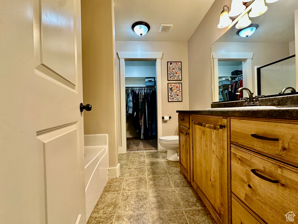 Full bathroom featuring a spacious closet, vanity, light tile patterned floors, and a shower stall