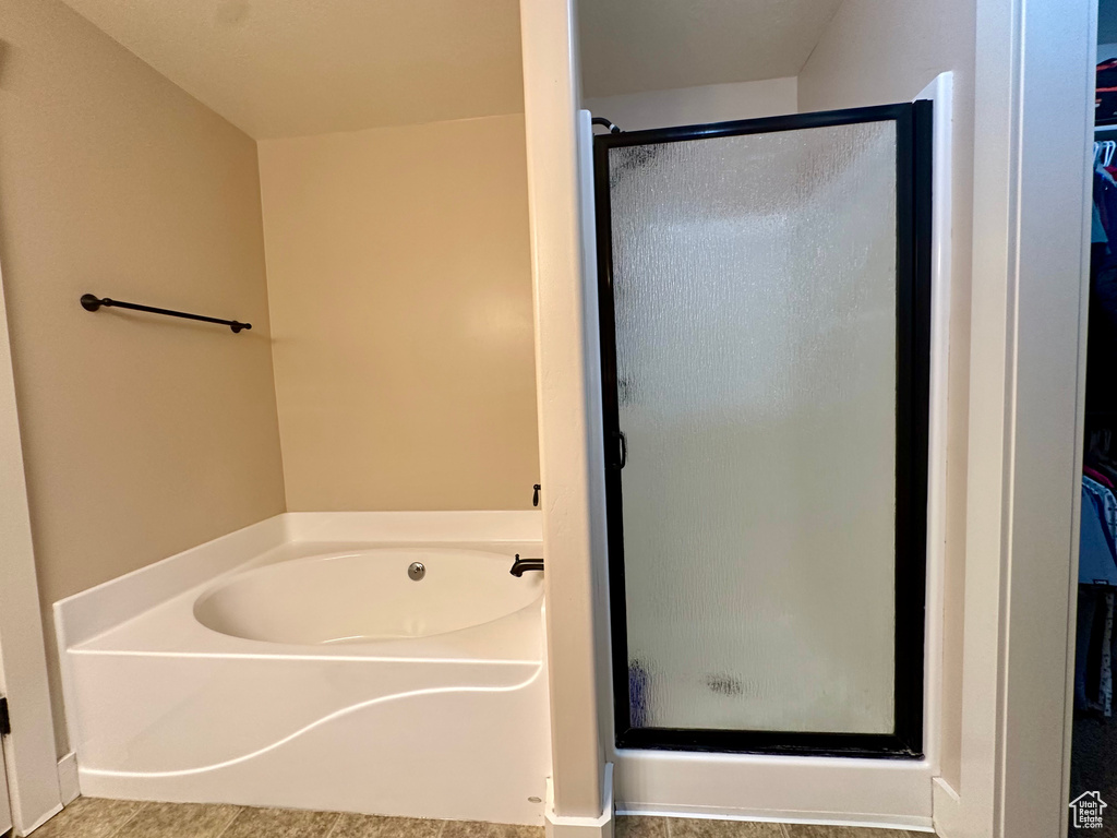 Full bath with a walk in closet, a shower stall, a garden tub, and tile patterned floors