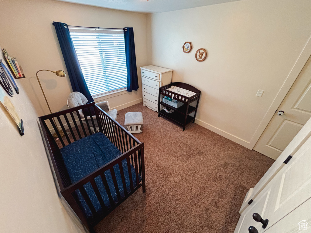 Bedroom featuring a nursery area and dark colored carpet