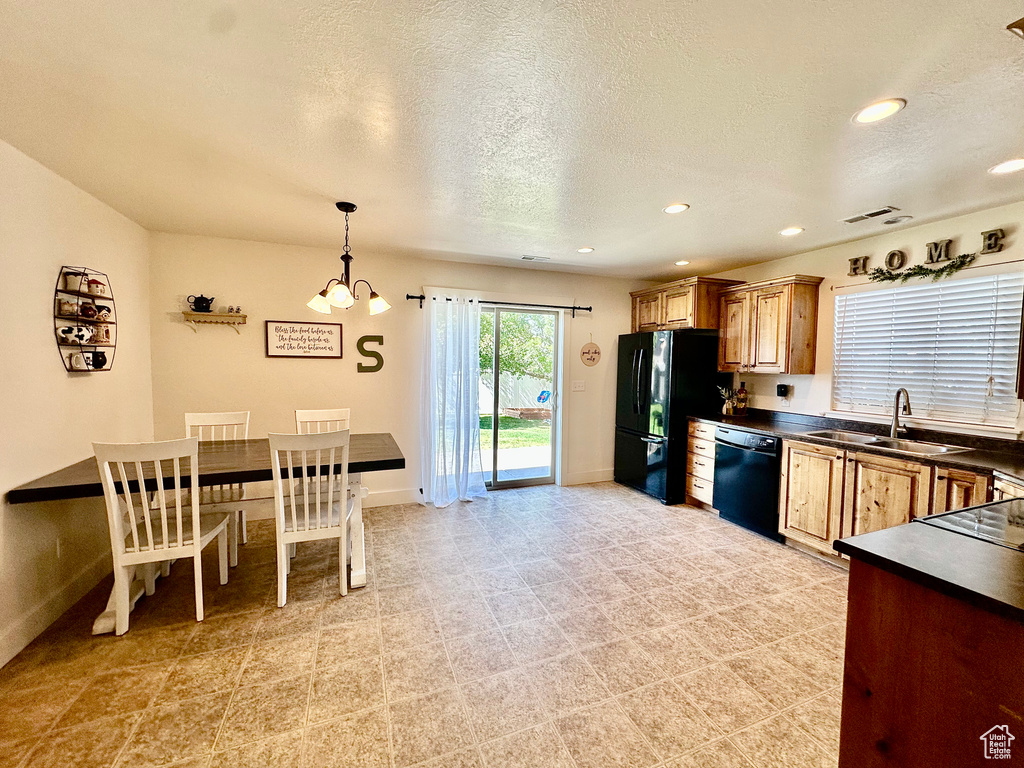Kitchen with dark countertops, hanging light fixtures, black appliances, a textured ceiling, and recessed lighting