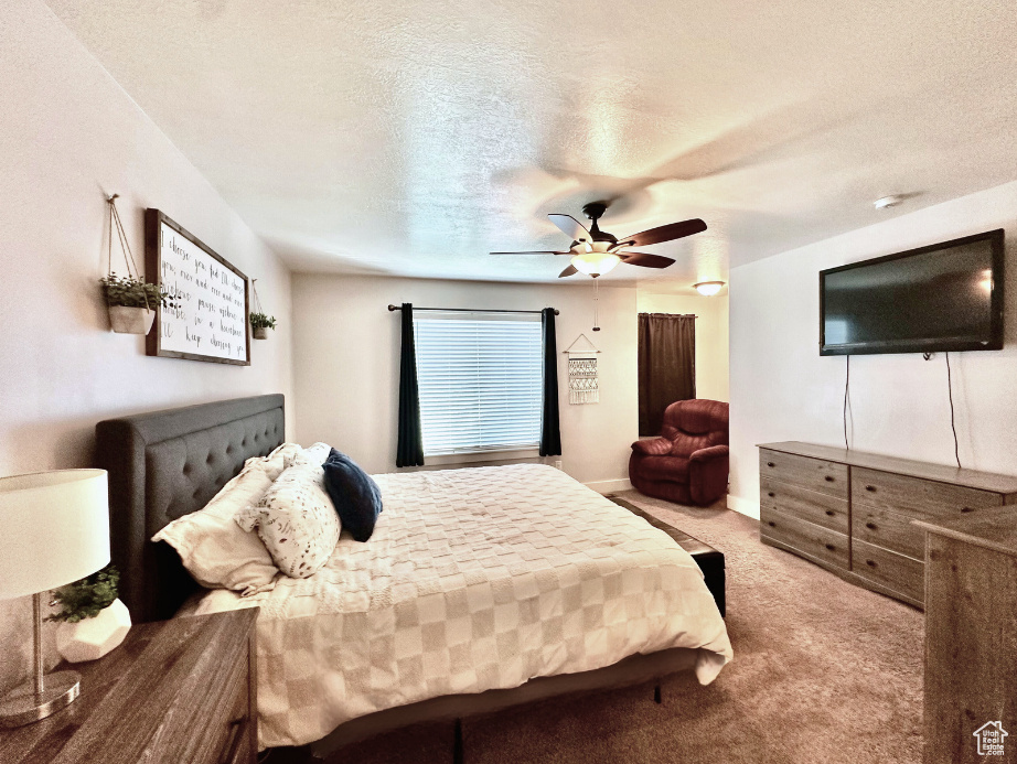 Bedroom featuring a textured ceiling, carpet flooring, and a ceiling fan