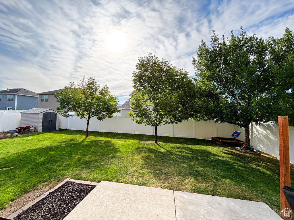 Fenced backyard featuring a storage unit and a patio