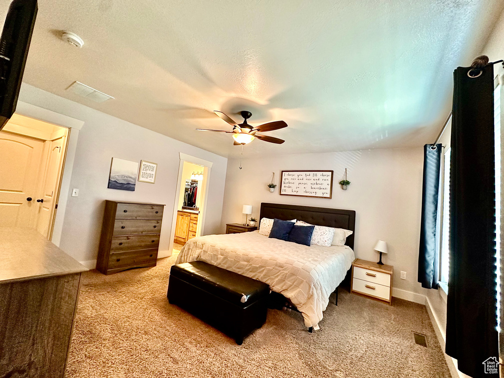 Bedroom featuring light colored carpet, a ceiling fan, ensuite bath, and a textured ceiling