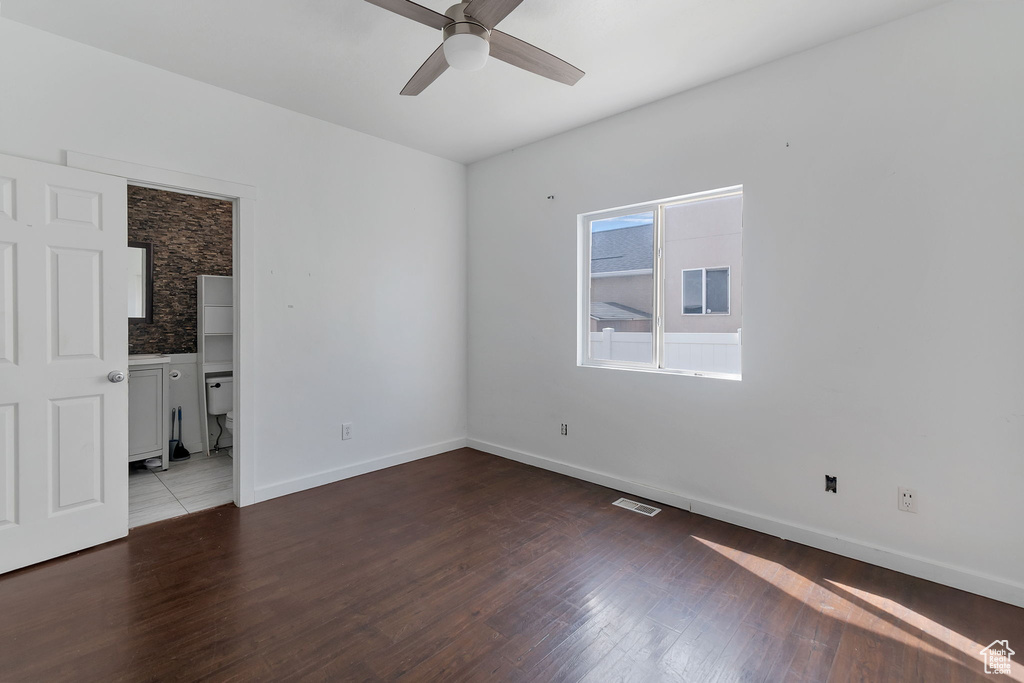 Empty room featuring dark wood-style flooring and a ceiling fan