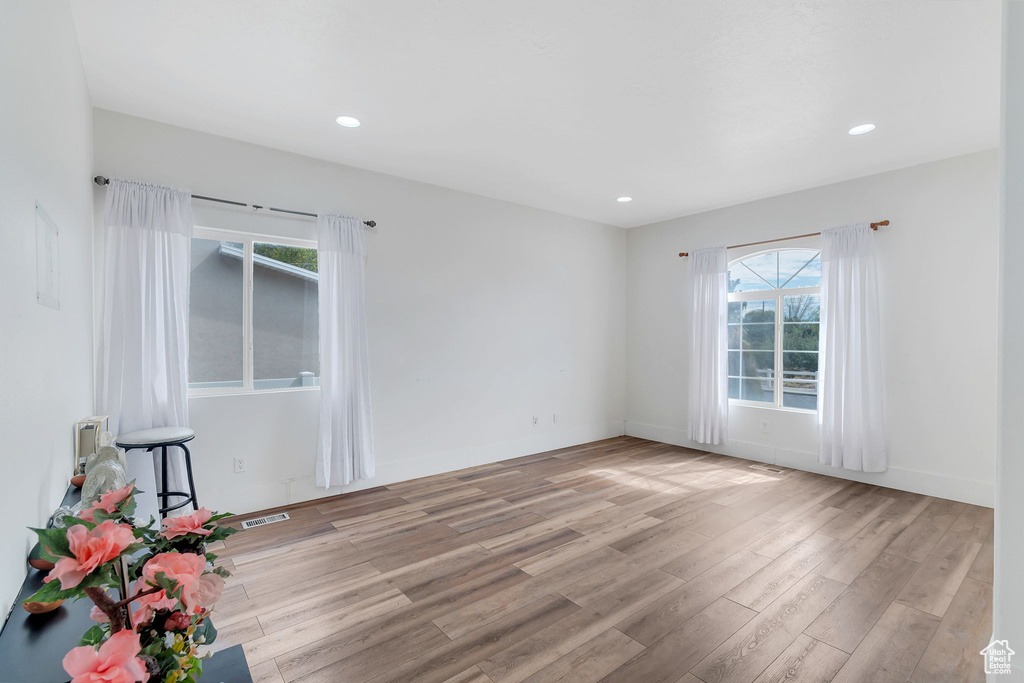 Empty room with light wood-style floors and recessed lighting