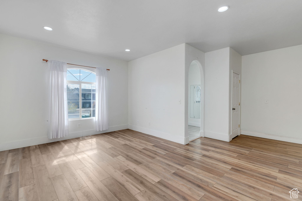 Unfurnished room with recessed lighting, light wood-style floors, and arched walkways