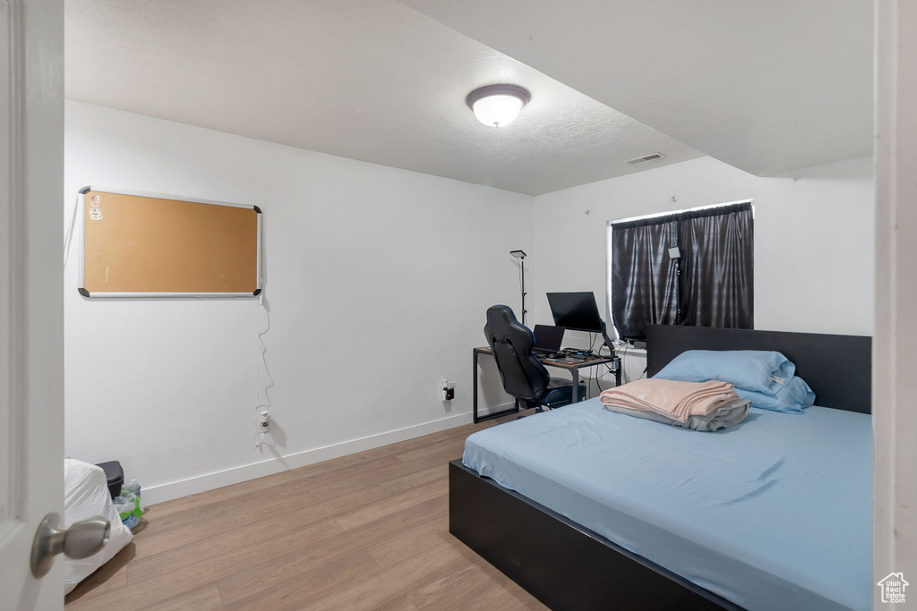 Bedroom featuring light wood-style flooring, a textured ceiling, and a desk