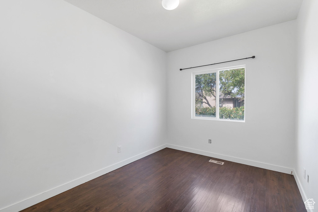 Unfurnished room featuring baseboards and dark wood finished floors