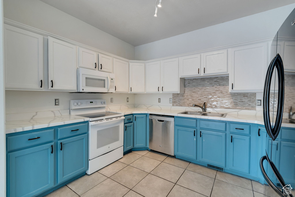 Kitchen with blue cabinets, white appliances, white cabinetry, backsplash, and light tile patterned flooring
