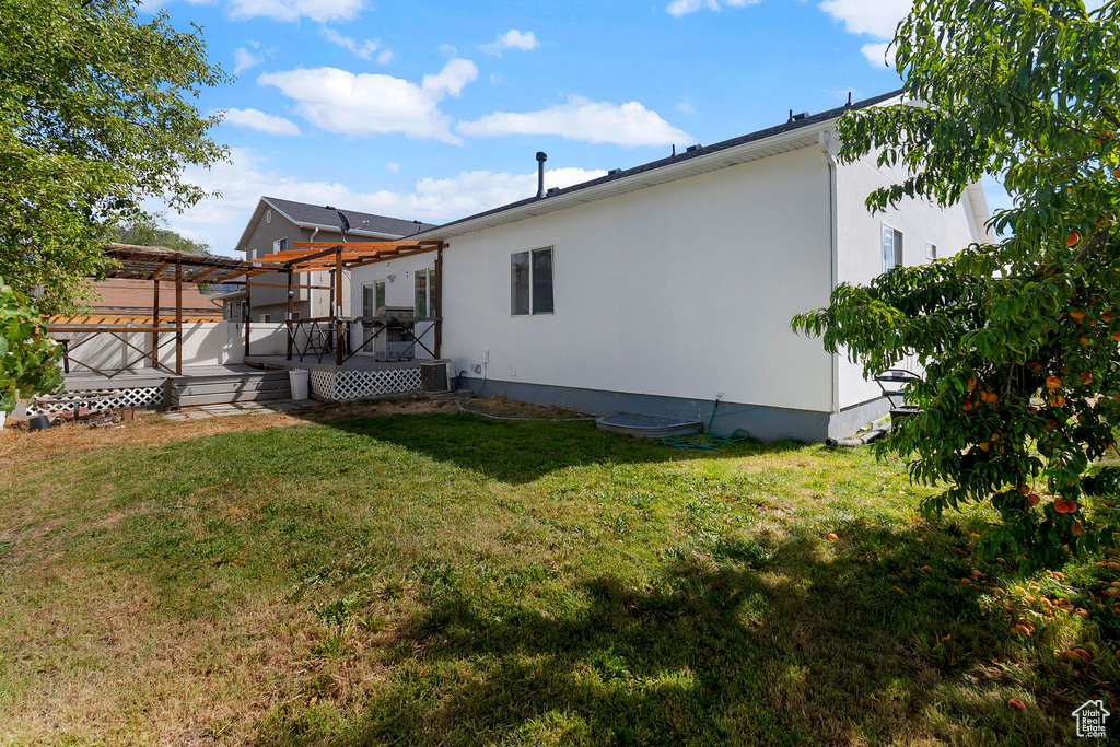 Rear view of property with stucco siding, a lawn, a deck, and a pergola
