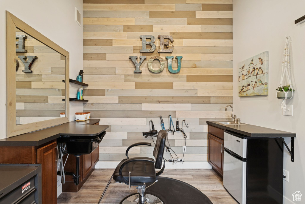 Kitchen featuring dark countertops, light wood-type flooring, wood walls, and freestanding refrigerator