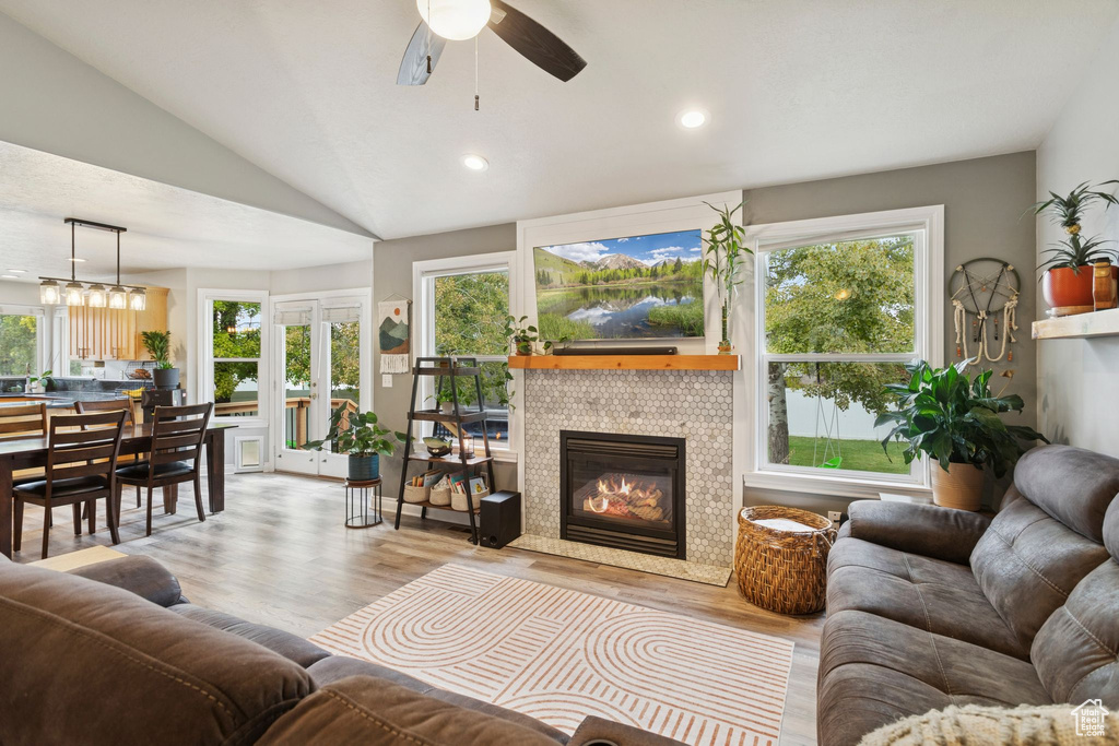 Living room featuring wood finished floors, lofted ceiling, a fireplace, recessed lighting, and ceiling fan