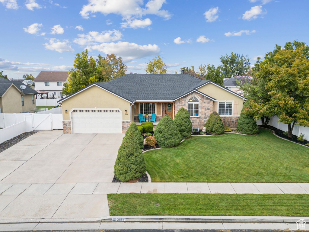 Single story home with stone siding, concrete driveway, a garage, a gate, and stucco siding