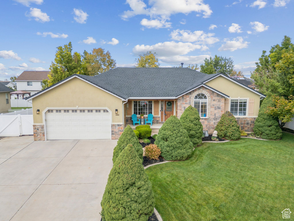 Ranch-style house featuring stone siding, covered porch, and driveway