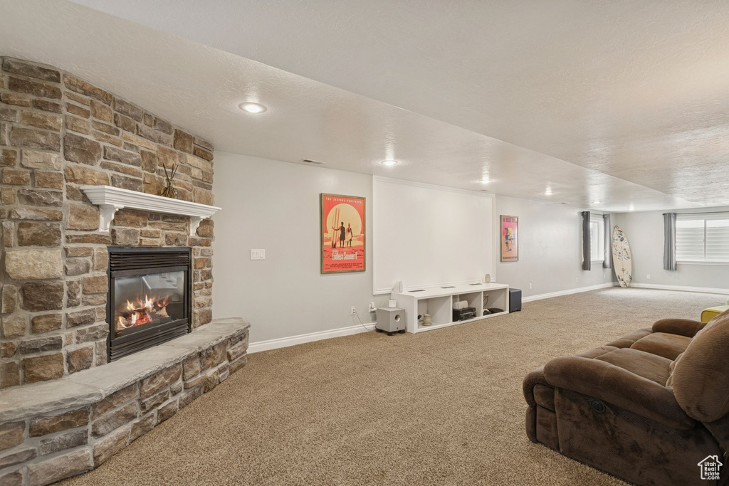 Carpeted living area with baseboards and a stone fireplace