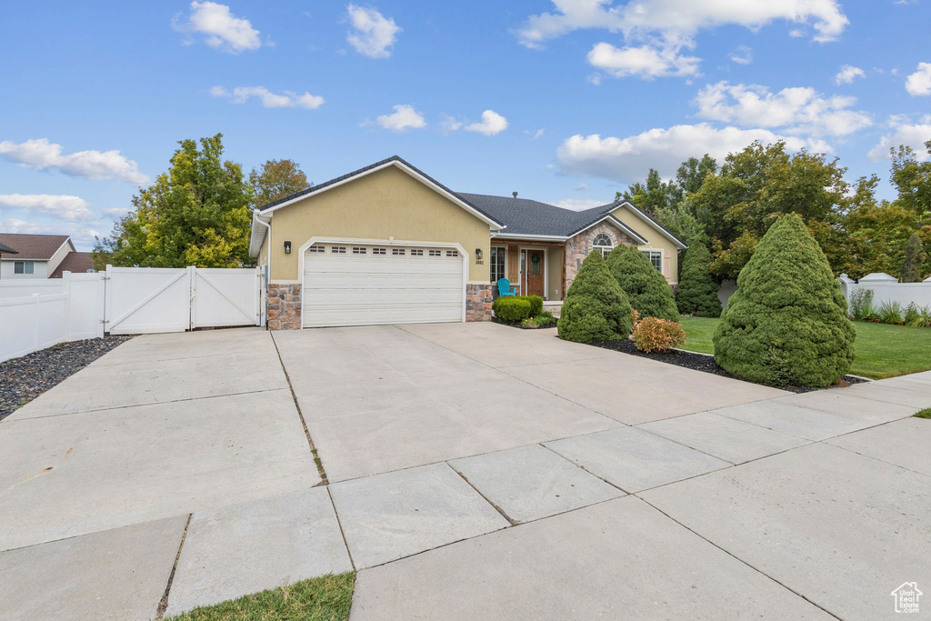 Ranch-style house featuring a gate, stone siding, concrete driveway, stucco siding, and a garage