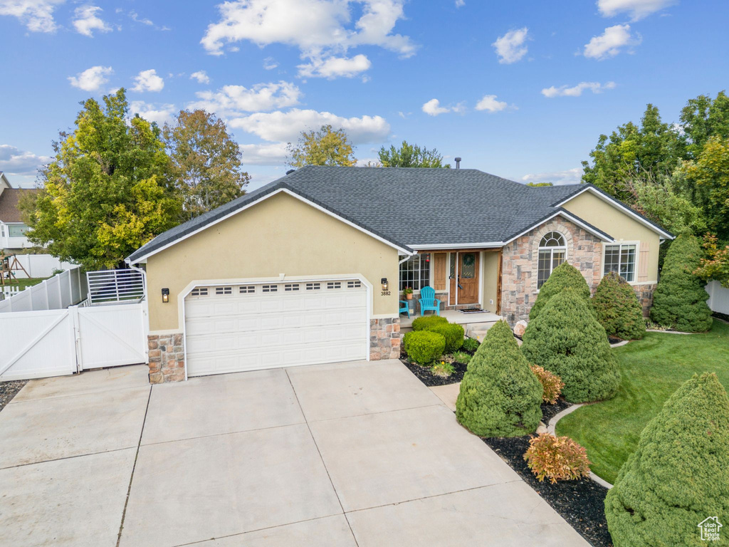 Ranch-style house with stone siding, a gate, concrete driveway, and stucco siding
