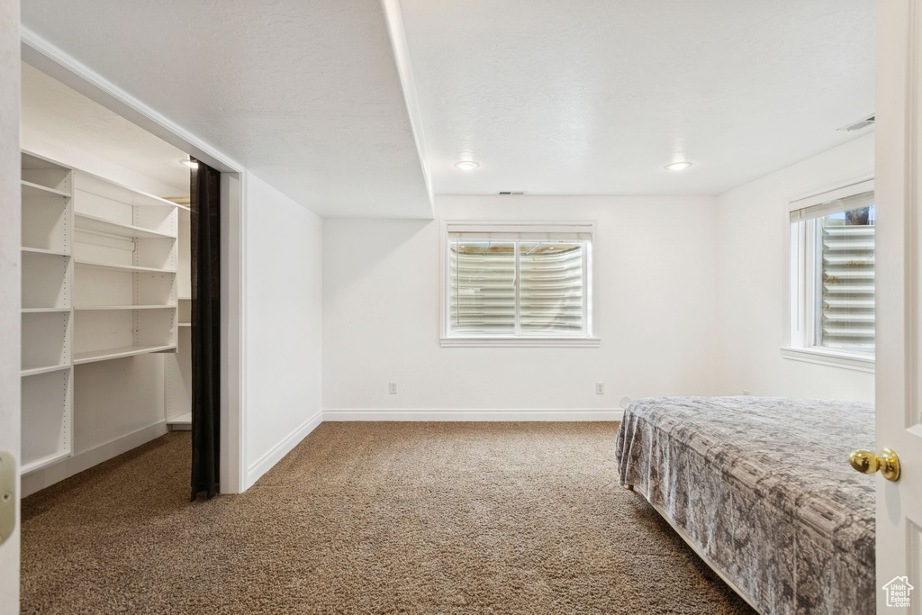 Bedroom featuring dark colored carpet and a spacious closet