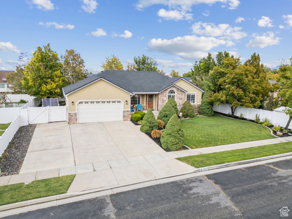 Single story home featuring a gate, stone siding, driveway, an attached garage, and stucco siding