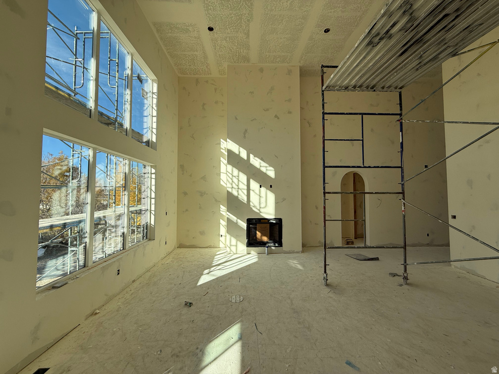 Unfurnished living room featuring a fireplace and a towering ceiling