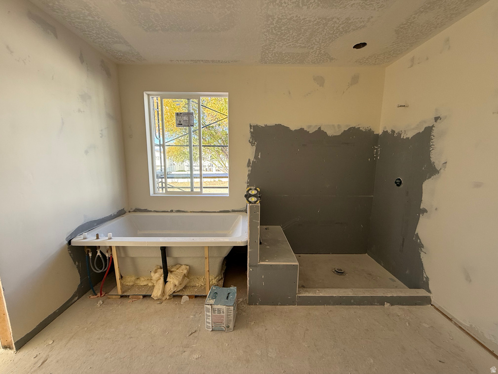 Full bath featuring a tub, walk in shower, and a textured ceiling