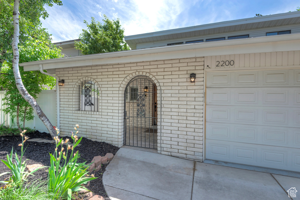 Doorway to property with brick siding and a garage
