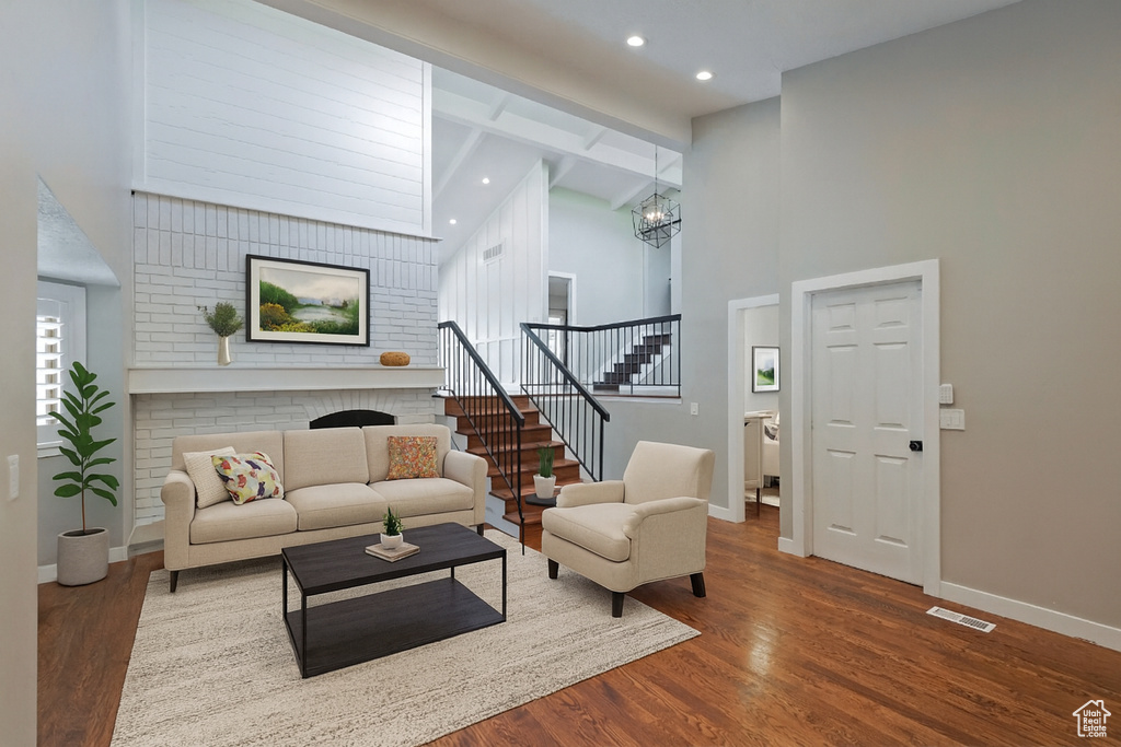 Living room with high vaulted ceiling, dark wood finished floors, stairs, a chandelier, and recessed lighting