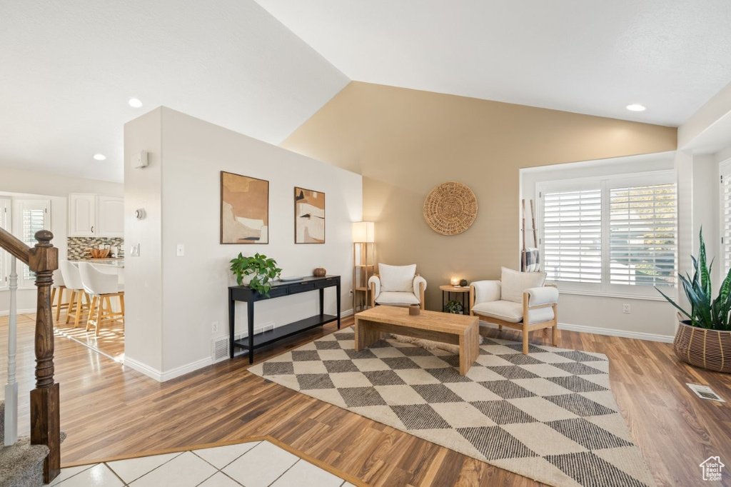 Living area with recessed lighting, light wood-style floors, stairs, and vaulted ceiling