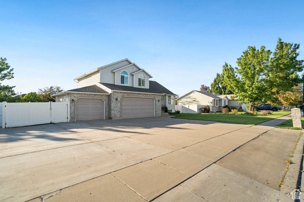 Traditional-style home featuring concrete driveway, brick siding, roof with shingles, a garage, and a gate