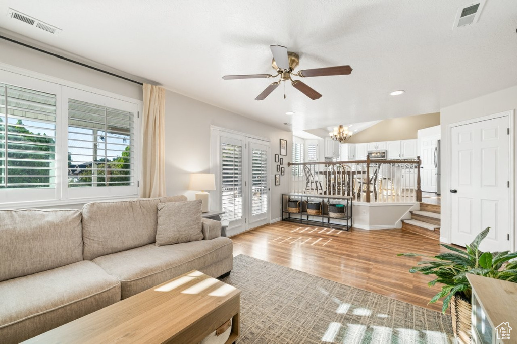 Living area with wood finished floors, recessed lighting, a ceiling fan, stairs, and a chandelier