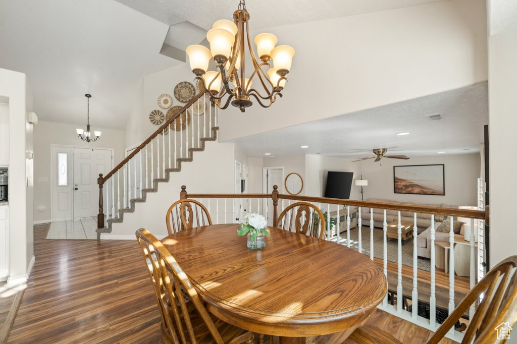 Dining space with a chandelier, wood finished floors, and stairway
