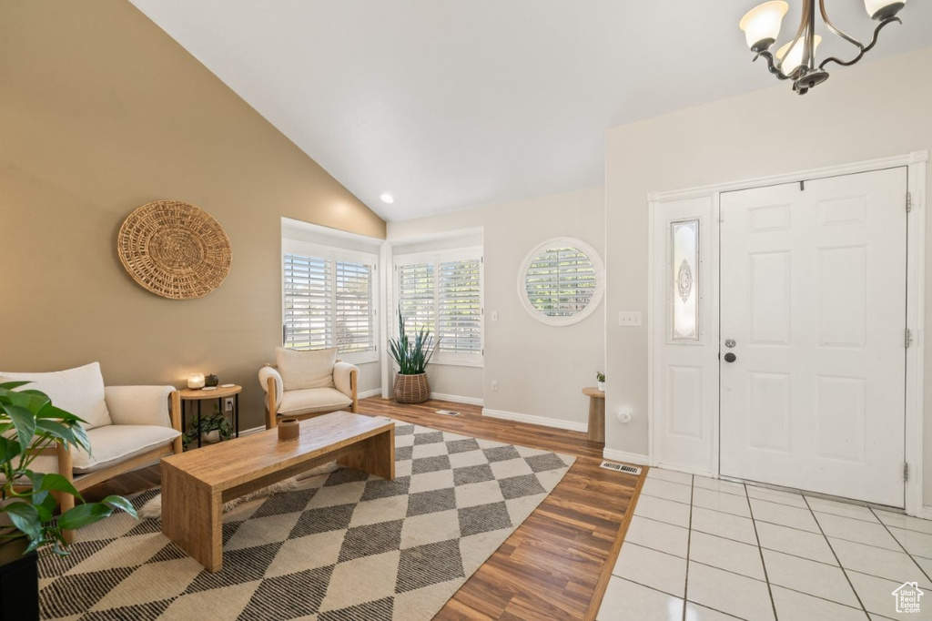 Entrance foyer featuring light wood-style floors, a chandelier, and high vaulted ceiling