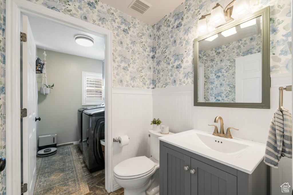 Bathroom featuring vanity, washing machine and dryer, and wainscoting