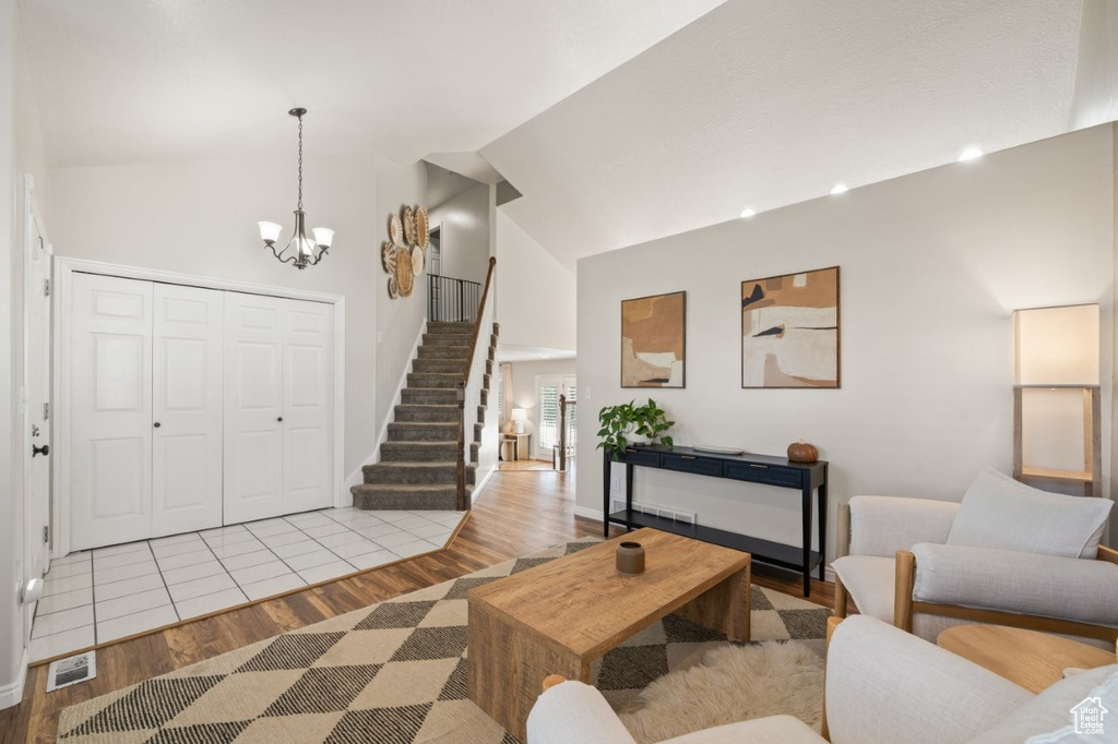 Foyer featuring light wood finished floors, high vaulted ceiling, stairway, and a chandelier