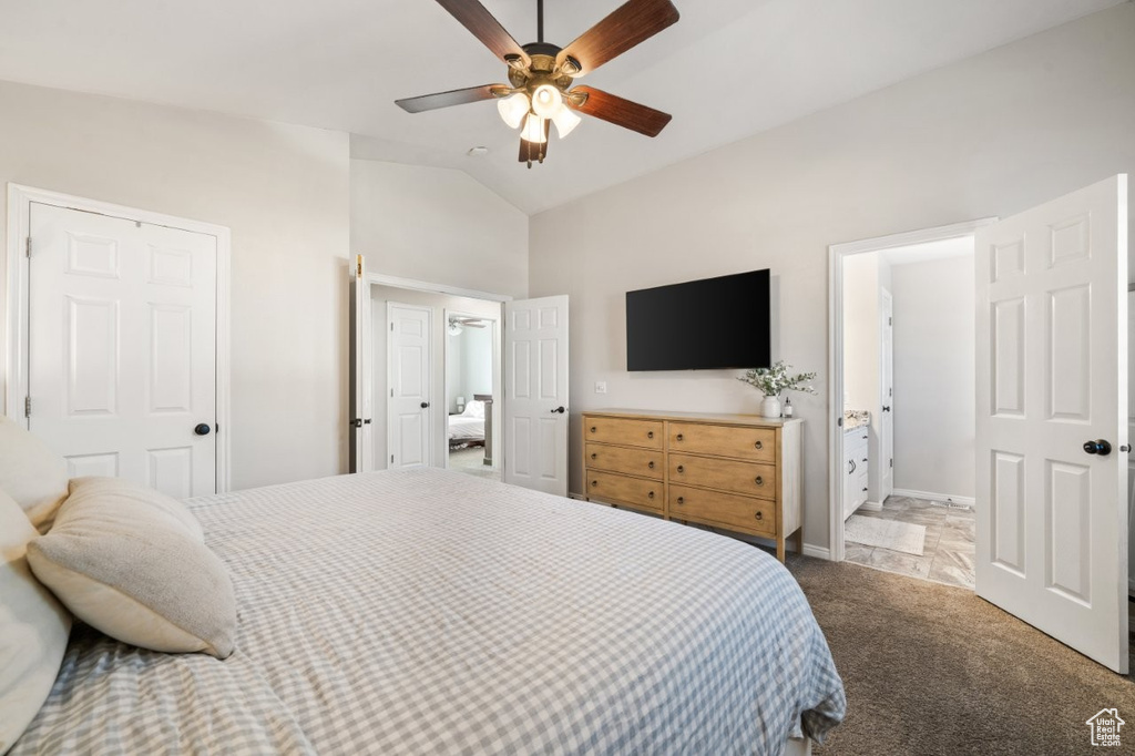 Bedroom with lofted ceiling, dark carpet, ceiling fan, and ensuite bath