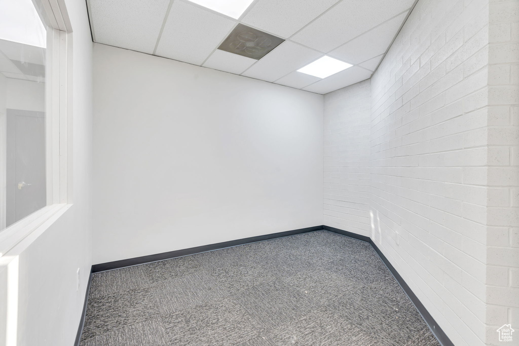 Carpeted empty room with a paneled ceiling and baseboards