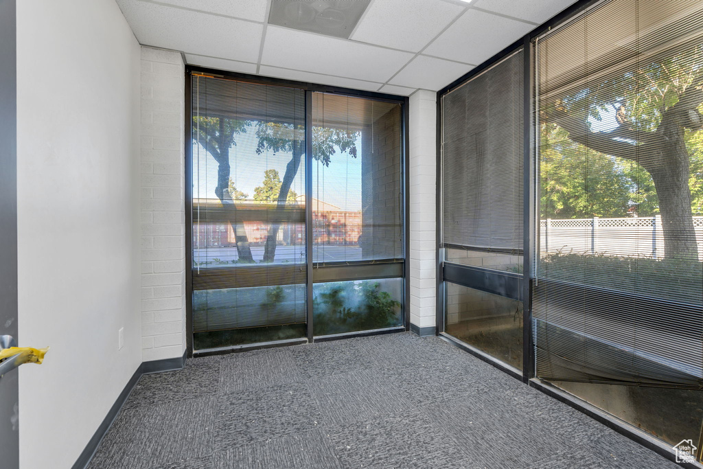 Carpeted spare room with a paneled ceiling and floor to ceiling windows