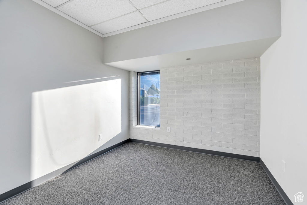 Carpeted empty room with baseboards and a paneled ceiling