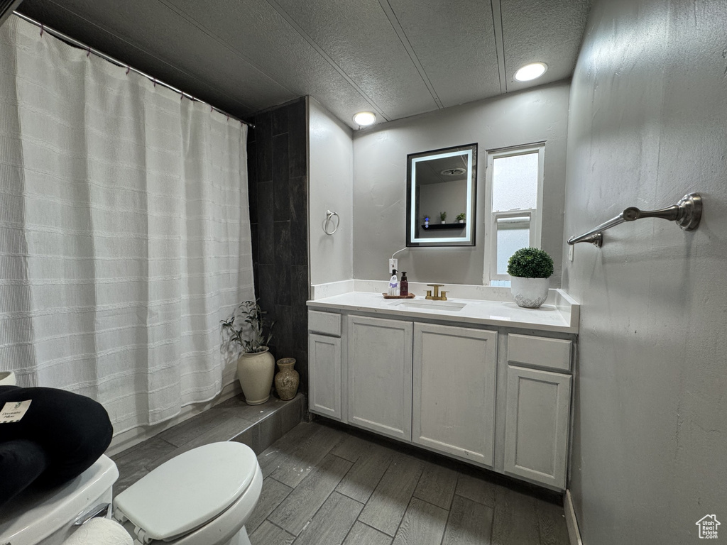 Full bath featuring a textured ceiling, vanity, dark wood-style flooring, and a shower with shower curtain