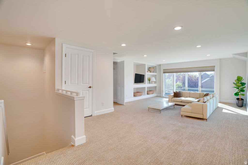 Carpeted living room with built in shelves and recessed lighting