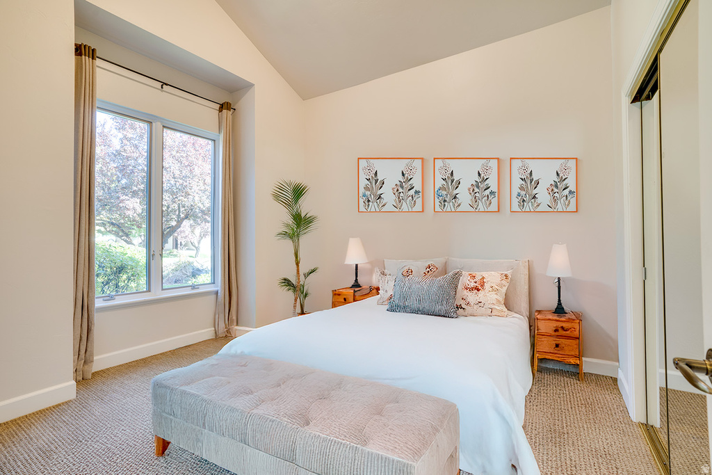 Bedroom with vaulted ceiling and light carpet