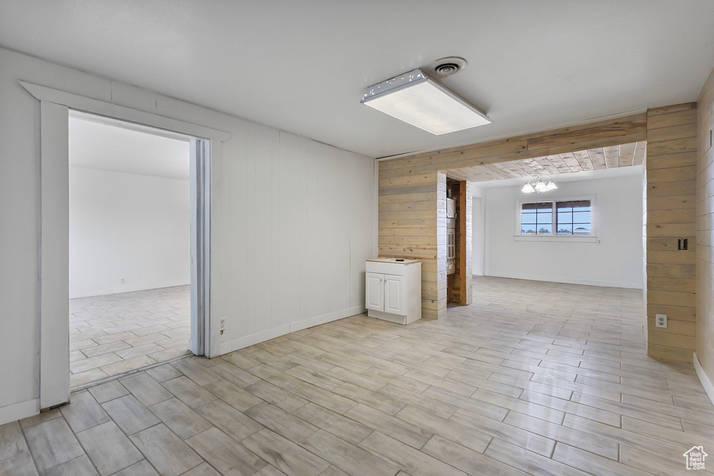 Spare room with wooden walls, wood finish floors, and a chandelier