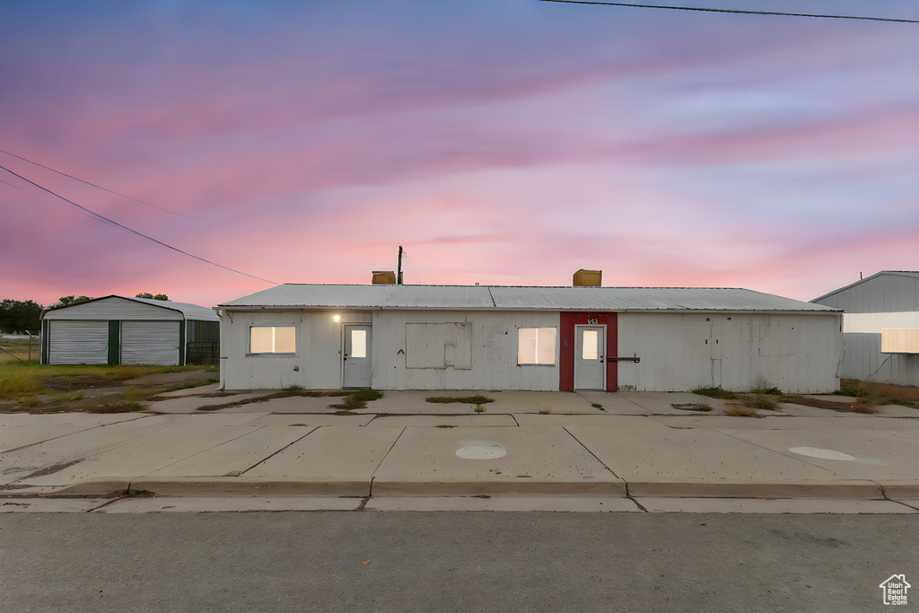 View of front of property with a metal roof, a detached garage, an outbuilding, and a chimney