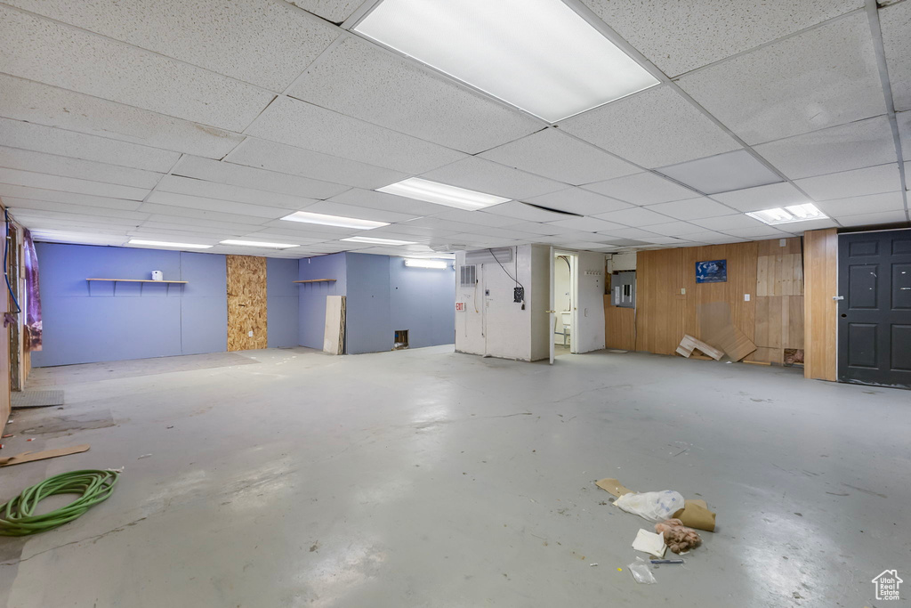 Below grade area featuring wooden walls and a drop ceiling