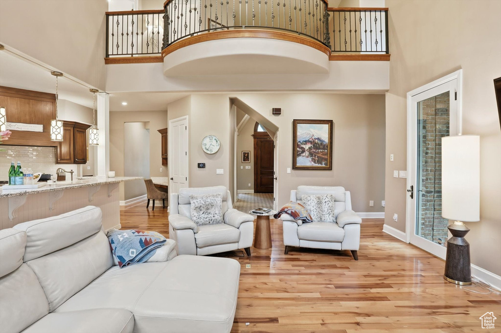 Living room with a high ceiling, light wood-style floors, and arched walkways