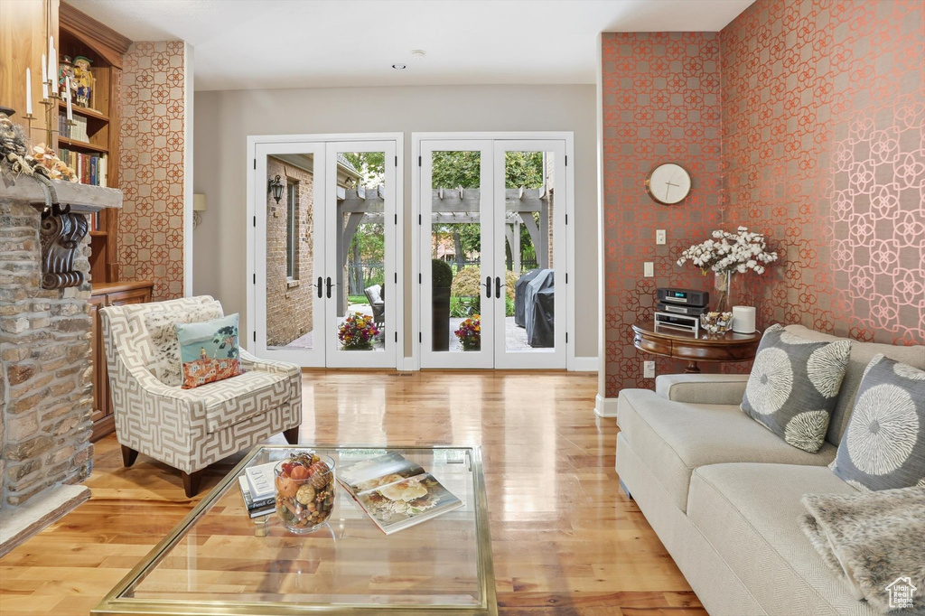 Sitting room featuring french doors, wallpapered walls, light wood-style flooring, and an accent wall