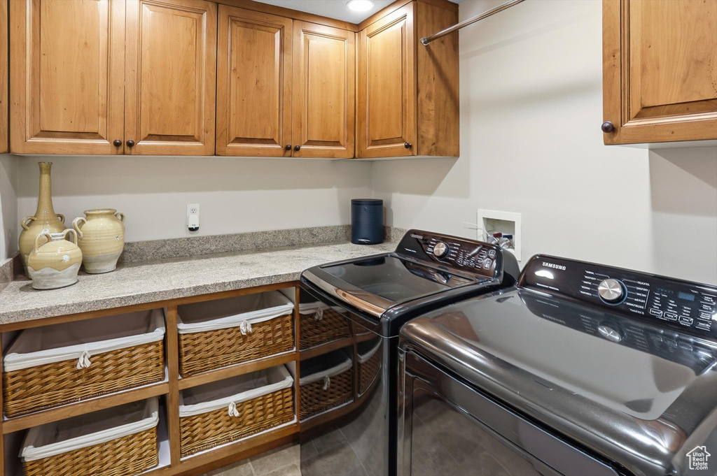 Washroom with cabinet space, washer and clothes dryer, and tile patterned flooring